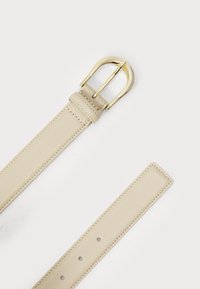 Beige lærbelte med en gullfarget metallspenne, med en jevn tekstur, flere justeringshull og pent søm langs kantene.