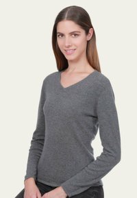 Pull gris à col en V avec manches longues, fabriqué en tissu doux. Texture lisse, coupe ajustée et style simple, idéal pour superposer.