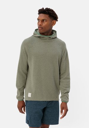 Felpa verde, textured con cappuccio ampio, maniche raglan e una piccola etichetta in tessuto riciclato sull'orlo, abbinata a pantaloni corti blu scuro.