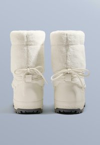 Hvide støvler foret med pels, med tekstureret overdel, rund tå og sorte gummisåler. Har sløjfer bagpå for justerbar pasform.