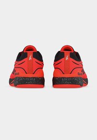 Ζευγάρι αθλητικά παπούτσια κόκκινου και μαύρου χρώματος από πίσω, με μαύρες ενδιάμεσες σόλες υφής με λευκές επάνω κηλίδες και λεπτομέρειες με λογότυπο.