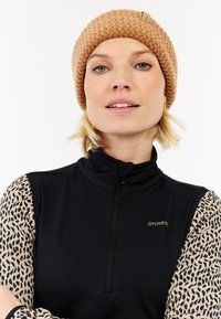 Zwarte zip-up top met mouwen inluipaardprint en een gebreide bruine beanie; heeft een klein logo in goud op de borst.
