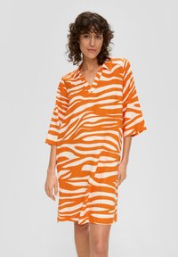Orangenes und weißes gestreiftes Kleid mit V-Ausschnitt und kurzen Ärmeln. Hergestellt aus leichtem Stoff, der auffällige zebraartige Muster aufweist.