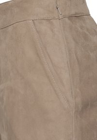 Beige Wildlederstoff mit einer weichen Textur und sichtbaren Nähdetails. Verfügt über einen unauffälligen Reißverschluss an der Oberseite und ein glattes, klares Design.