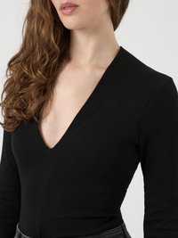 Svart longsleeve bodysuit med dyp V-hals og ribbestruktur, som gir en tettsittende design. Ingen synlig hardware eller detaljer.