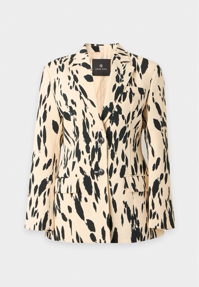 Blazer beige pour femme avec taches abstraites noires, deux boutons, col cranté et poches à rabat, présenté sur fond gris clair.