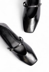 Scarpe flat nere in pelle con punta quadrata, dotate di una sottile fascia con una fibbia rotonda e una texture liscia e lucida.