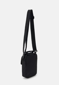 Black shoulder bag with a rectangular shape, made of textured fabric, featuring a long adjustable strap and a zippered closure.