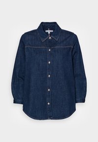 Camicia in denim blu scuro con maniche lunghe, chiusura frontale con bottoni, colletto appuntito e cuciture in contrasto. Orlo arrotondato e accento del logo discreto.