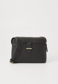Sac en bandoulière en cuir noir avec une surface texturée, quincaillerie dorée, fermeture éclair et bandoulière réglable. Forme rectangulaire compacte.