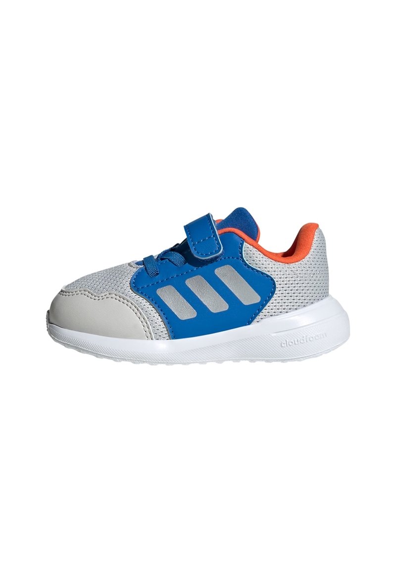 Szary sneaker z niebieskim paskiem na rzep, siateczkową cholewką, srebrnymi akcentami i pomarańczowym tyłem. Lekki z białą, teksturowaną podeszwą.