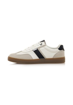 Zapatillas blancas y beige con acentos negros, materiales de cuero y gamuza, diseño con cordones, suela de goma con un acabado texturizado.