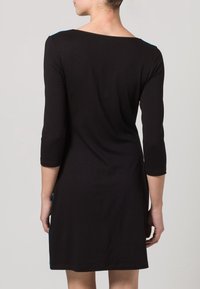 Robe noire à manches trois-quarts, décolleté large et silhouette ajustée, avec une bordure bleue contrastante sur les côtés.