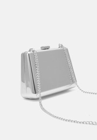 Silvermetallisk kuvertväska med rektangulär form, utrustad med ett gångjärnslås och en silverkedjestrap. Slät, reflekterande yta utan synliga mönster.