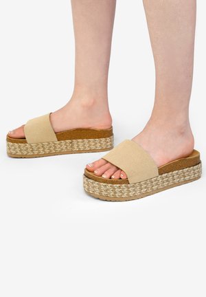 Sandalias de plataforma beige con una amplia tira suave, plantilla de yute trenzado y suela de goma. El acolchado proporciona comodidad y estabilidad.