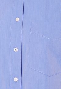 Blå och vit tunn vertikalrandig skjorta fram med vita knappar och en synlig bröstficka på höger sida.