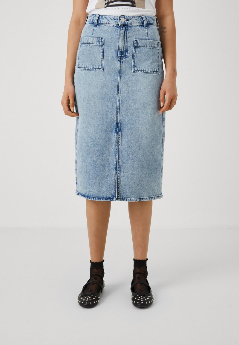 Fustă din denim albastru deschis, cu un croi până la genunchi, buzunare frontale și un talie clasică cu închidere cu button. Marginea uniformă și decolorare subtilă.