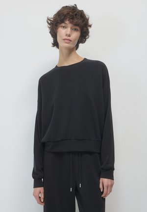 Sweatshirt en mélange de coton noir avec une coupe décontractée, un col rond, des épaules tombantes et un ourlet côtelé. Il présente une texture lisse et un design minimaliste.