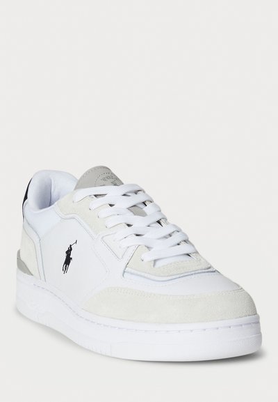 White sneaker with suede and leather panels, grey accents, prominent logo, textured stitching, and a thick rubber sole.