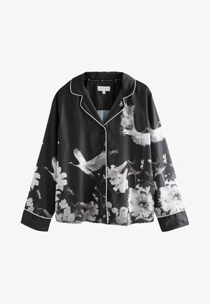 Must musta pükskostüüm koos valge äärepitseriga, millel on lille- ja tõsise print. Pika varrukaga, nupuga ees ja lõdva istuvusega.