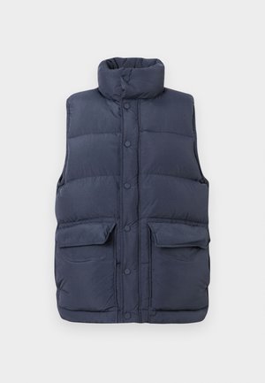 Vesta căptușită de culoare bleumarin, cu guler înalt, nasturi cu clips în față și două buzunare mari în față. Fabricată dintr-un material ușor, matlasat.