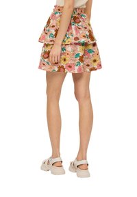 Mini-jupe à motifs floraux avec volants superposés, présentant des teintes de rose, jaune et marron. Taille élastique. Complète les chaussures décontractées.