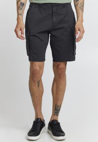 Shorts cargo noirs pour homme en mélange de coton, avec poches latérales, coupe décontractée et détails cousus. Assortis avec des baskets noires.