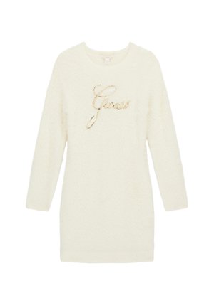 Robe-pull duveteuse à manches longues de couleur crème avec logo "Guess" en cursive dorée sur le devant.