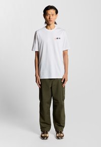 Hvid bomulds T-shirt med et lille grafisk print på venstre bryst, parret med olivengrønne cargo bukser med sidelommer og en afslappet pasform.