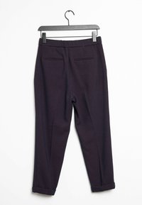 Mörkblå byxor med ett subtilt diamantmönster, med en kroppsnära design, uppvikta fållar och två bakfickor. Hänger från en svart krok.