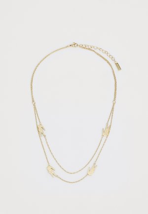 Colier cu ton auriu, compus din două lanțuri suprapuse cu pandantive în formă de mână și închidere cu broșă, evidențiat de o mică etichetă.