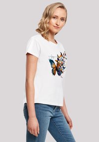 Weißes Baumwoll-T-Shirt mit einem Schmetterlings-Graphic in Blau-, Orange- und Gelbtönen, mit kurzen Ärmeln und einer lockeren Passform.