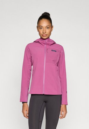 Lyserød letvægtsjakke med hætte, chevronstruktur og lynlåslommer, kombineret med tætsiddende sorte leggings.