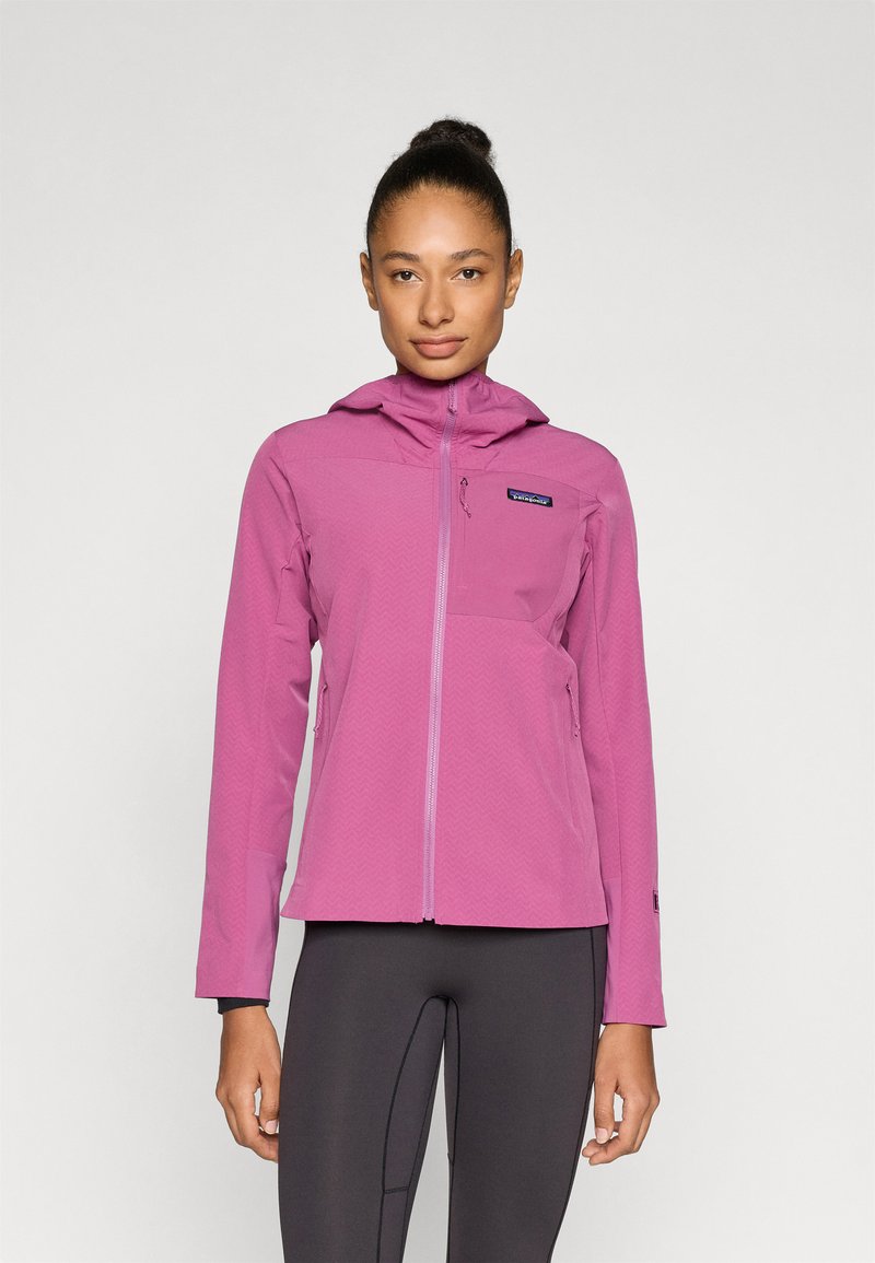 Ροζ ελαφρύ μπουφάν με κουκούλα, υφή σε σχήμα βέλους και τσέπες με φερμουάρ, συνδυασμένο με εφαρμοστά μαύρα κολάν.