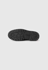 Semelle de botte en caoutchouc noir avec un motif de sculpture texturé présentant des formes arrondies et angulaires, une marque en relief et de profondes rainures pour l'adhérence.