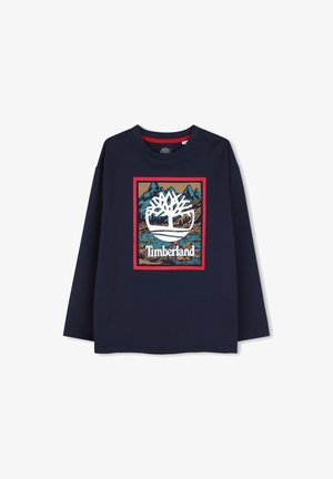 Marineblauw overhemd met lange mouwen met een groot Timberland-logo met een witte boom boven een berg- en rivierlandschap in een rood omrande rechthoek.
