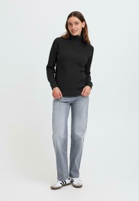 Pulover negru cu guler înalt, cu mâneci lungi, asortat cu blugi drepți gri deschis și adidași albi cu dungi negre.