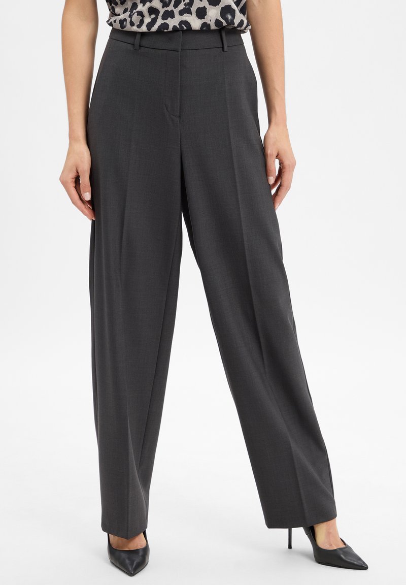 Koolgrijze wijde broek gemaakt van een soepele stof, met voorzakken en een op maat gemaakte tailleband. Gepaarde met zwarte puntige hakken.
