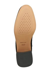 Podeszwa czarnego formalnego buta z beżowym przodem i czarnym, żebrowanym obcasem, z otworami wentylacyjnymi oraz napisem "GEOX Italian Patent".