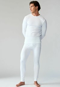 Cămașă albă termică cu mâneci lungi și pantaloni ajustați, dintr-un material moale și elastic. Textura canelată, cu guler rotund și manșete conice.