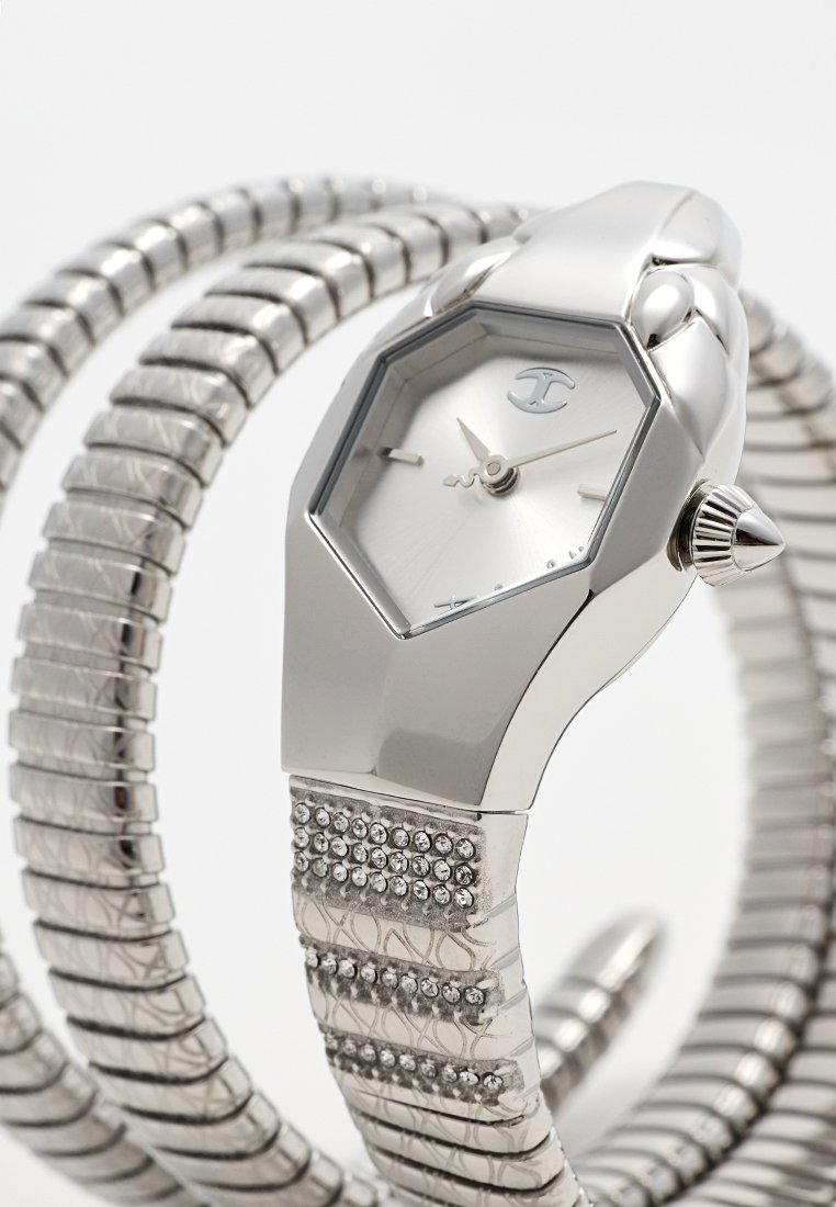 Reloj hexagonal en tono plateado con una correa texturizada, que cuenta con una esfera reflectante y acentos decorativos de cristal en la correa.