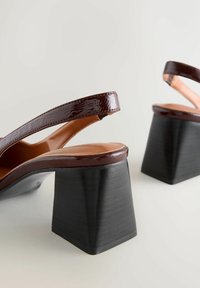 Rudos lakuoto odos slingback batai su plačiais kvadratiniais juodais kulnais ir lygiais tan spalvos pamušalais. Išskirtinis minimalistinis dizainas su elegantiškomis linijomis.
