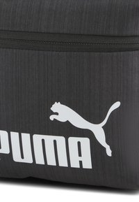 Grå stofpose med lynlås, stort hvidt "PUMA" logo og en springende katte-silhuet. Den teksturerede overflade giver visuel interesse.