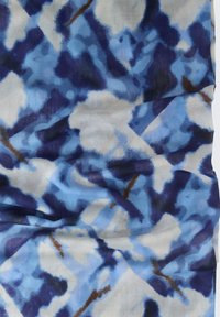 Blauwe en witte stoffen met een patroon van abstracte vormen, met variërende tinten blauw en lichte bruine accenten, zachte textuur.