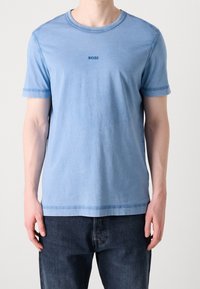 Jasnoniebieska bawełniana koszulka z krótkimi rękawami, okrągłym dekoltem i małym logo "BOSS" na piersi. Miękka tekstura i swobodny krój.
