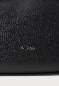 Geantă de mână neagră din piele cu o suprafață texturată. Prezintă un logo auriu în relief cu inscripția „GIANNI CHIARINI FIRENZE” pentru branding.