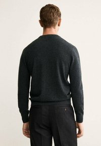 Dunkelgrauer gestrickter Pullover mit Rundhalsausschnitt und langen Ärmeln, ausgestattet mit gerippten Bündchen und Saum, kombiniert mit gestreiften Hosen.