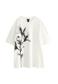 Hvid t-shirt med et sort blomsterdesign på venstre side. Har en rund halsudskæring, korte ærmer og en blød, let tekstur.