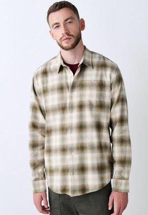 Beige en bruine geruite flanellen shirt met knopen aan de voorkant, één borstzak en lange mouwen. Zachte textuur, gebogen zoom.