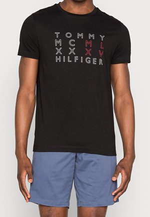 Schwarzes Baumwoll-T-Shirt mit weißem und rotem Text "TOMMY HILFIGER" und numerischen Details, Rundhalsausschnitt und kurzen Ärmeln.